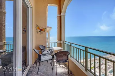 a balcony with chairs and tables and the ocean at 2 BR Monthly beach condo Miami in Hallandale Beach