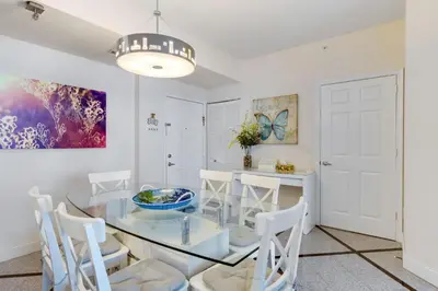 a dining room with a glass table and white chairs at 2 BR Monthly beach condo Miami in Hallandale Beach