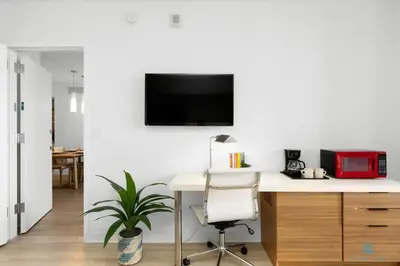 a living room with a desk and a tv on a wall at Beachwalk Resort: Amaizing View Balcony Gym Pool in Hallandale Beach