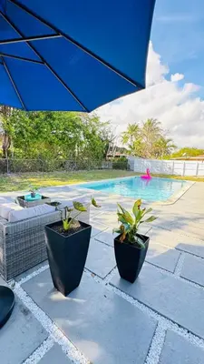 two potted plants sitting next to a swimming pool at Stylish Pool Home in Hollywood