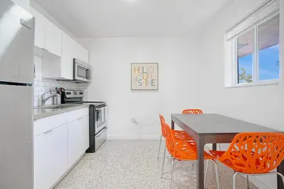 a kitchen with a table and two orange chairs at Elegant Wynwood Flats in Miami