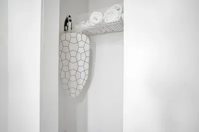 a white closet with a rack of towels and a shoe rack at Elegant Wynwood Flats in Miami