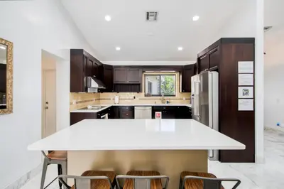 a kitchen with a white counter top and wooden cabinets at Marble House in Lauderdale Harbours in Fort Lauderdale