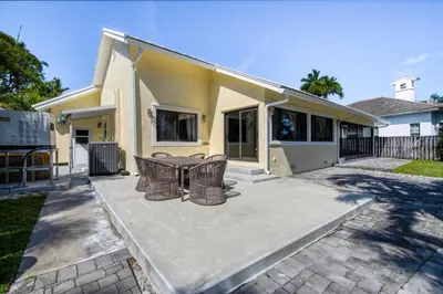 a patio with a table and chairs in front of a house at Marble House in Lauderdale Harbours in Fort Lauderdale