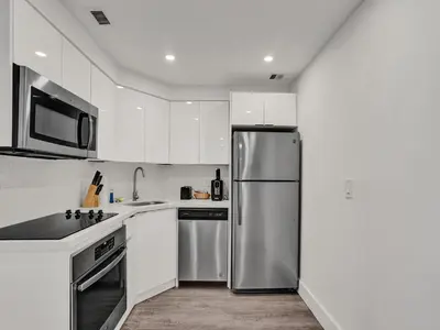 a kitchen with white cabinets and a stainless steel refrigerator at Gorgeous Miami Beach Condo 1614 in Miami Beach
