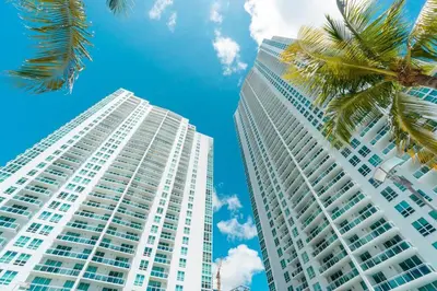 a tall white building with a palm tree next to it at Brickell High Rise Living at its best! w/ Pool Gym in Miami