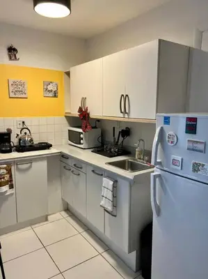 a kitchen with white cabinets and a sink and a refrigerator at Cozy apartment near Seminole Hard Rock Cafe in Hollywood