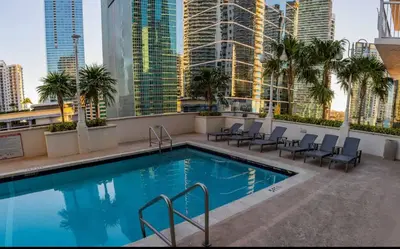 a pool on the roof of a building with chairs and palm trees at Luxe 1 BDR • 32th Floor • Brickell • Ocean Views in Miami
