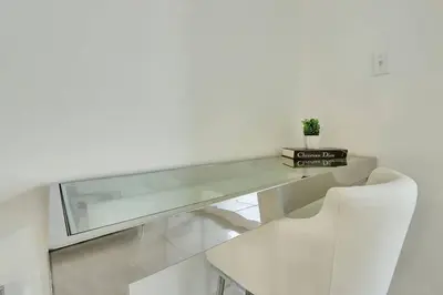 a glass desk with a white chair and a plant on it at Lux 1B condo with XL Balcony, Pool, Gym & Games in Miami