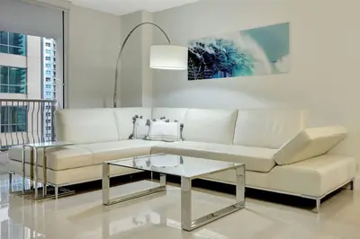 a living room with a white couch and a glass table at Lux 1B condo with XL Balcony, Pool, Gym & Games in Miami