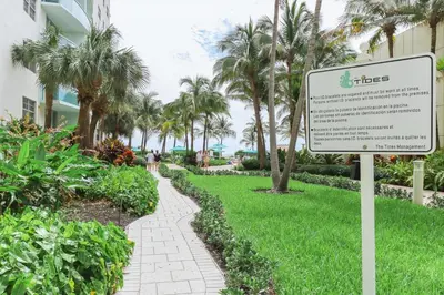 a sign in the grass next to a walkway at 2Bed/2Bath, 4QueenBeds & OceanView at Tides in Hollywood