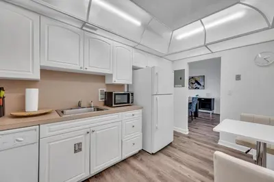 a white kitchen with a sink and a refrigerator at Spacious 1 BDR 1.5 BTH • Hallandale Beach in Hollywood