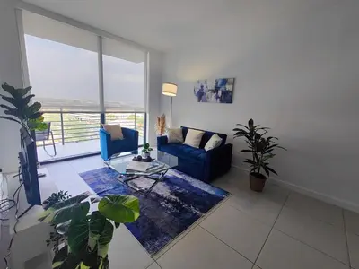 a living room with a blue couch and a table at Stylish 1-Bedroom Getaway Apt- pool & gym in Miami