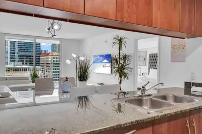a kitchen with a sink and a living room at LUX 1 BDR 1 BTH • Brickell • Pool & Ocean Views in Miami