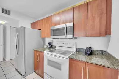 a kitchen with white appliances and wooden cabinets at LUX 1 BDR 1 BTH • Brickell • Pool & Ocean Views in Miami