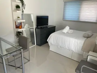 a bedroom with a bed and a tv and a chair at Studio close to airport in Dania Beach