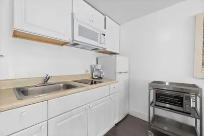 a kitchen with white cabinets and a sink and a microwave at 1 Bedroom Jr Suite - Ocean Drive & 6th Str in Miami Beach