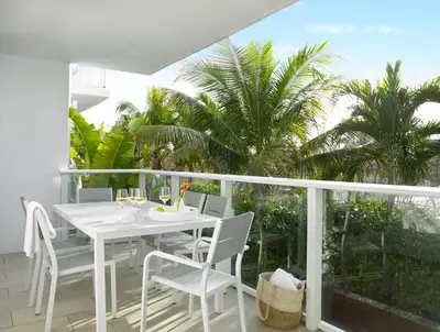 a white table and chairs on a balcony with palm trees at Grand Beach Hotel Surfside West in Miami Beach