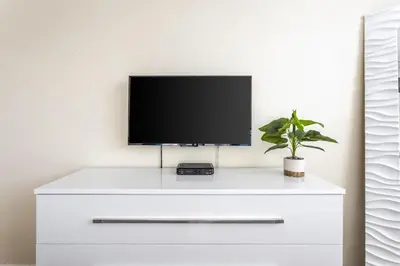 a tv on top of a white dresser with a plant at Sunny Isles Ocean Reserve Condo Apartments in Miami Beach