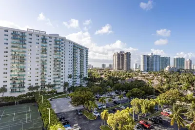 an apartment building with a tennis court in a parking lot at Sunny Isles Ocean Reserve Condo Apartments in Miami Beach