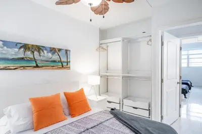 a bedroom with white walls and a bed with orange pillows at Sunny Isles Ocean Reserve Condo Apartments in Miami Beach