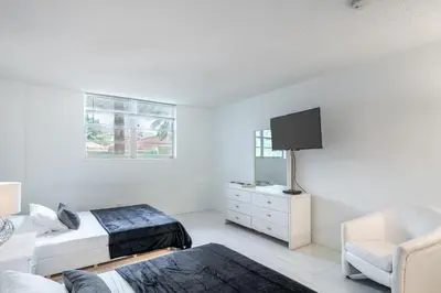 a bedroom with two beds and a tv and a chair at Sunny Isles Ocean Reserve Condo Apartments in Miami Beach