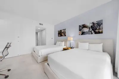 a white bedroom with two beds and a table at Beachwalk 2 Bedrooms with Kitchen 2 Bathroom & Gym in Hallandale Beach