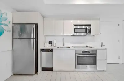 a kitchen with white cabinets and a stainless steel refrigerator at Beachwalk 2 Bedrooms with Kitchen 2 Bathroom & Gym in Hallandale Beach