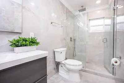 a bathroom with a toilet and a glass shower at Breathtaking 5BR & 3BA Villa near Hollywood Beach in Hollywood