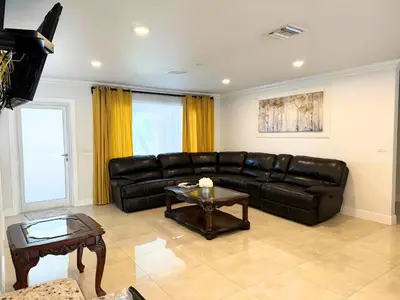 a living room with a leather couch and a table at Spacious 4/4 Home Central To All Attractions in Hollywood
