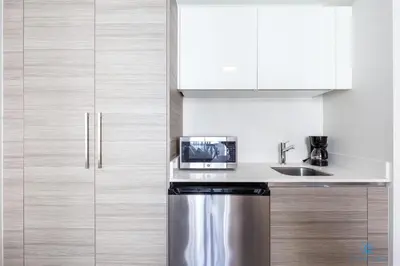 a kitchen with white cabinets and a stainless steel refrigerator at Studio - Steps from Hollywood Boardwalk in Hollywood