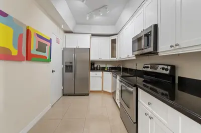 a kitchen with white cabinets and a stainless steel refrigerator at PROMO Komffy Penthouse w King Bed and Ocean view at Tides 16th floor in Hollywood