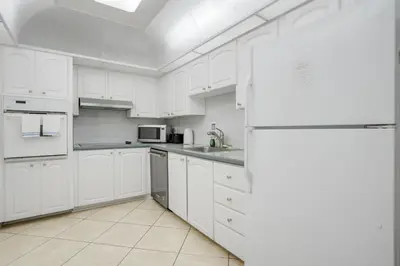 a white kitchen with white cabinets and a refrigerator at PROMO Komffy Home with King Bed & Ocean View at Tides 7th floor in Hollywood