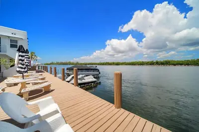 a dock with chairs and a boat on the water at Waterside Studio w/ King bed - Hollywood in Hollywood