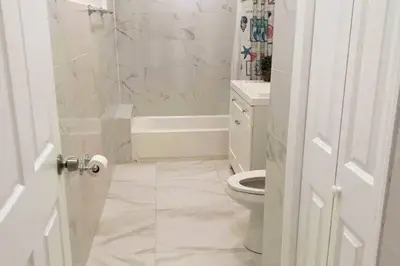 a white bathroom with a toilet and a shower at Brickell + Wynwood Wonderland: Spacious 6BR Home in Miami