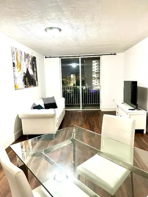 a living room with a glass table and white chairs at Private bedroom 1 block from Downtown Miami in Miami
