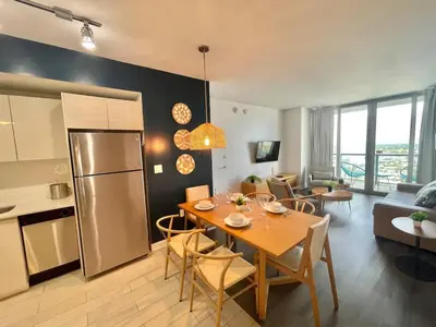 a kitchen and living room with a table and a refrigerator at 2BR-2BA Oasis W-Stunning Views at Beachwalk in Hallandale Beach