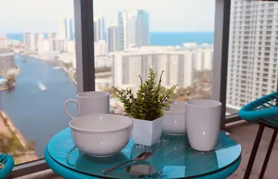 a glass tray with cups and a potted plant on a balcony at Beachwalk -1 Bedroom W-Kitchen and Great Views in Hallandale Beach