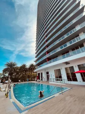 a person in a swimming pool next to a tall building at Beachwalk Studio W-Kitchenette Beach Pool Gym in Hallandale Beach