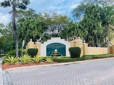 a building with a sign in a park with palm trees at 2 Luxury Bedrooms at Yacht Club de Aventura in Miami