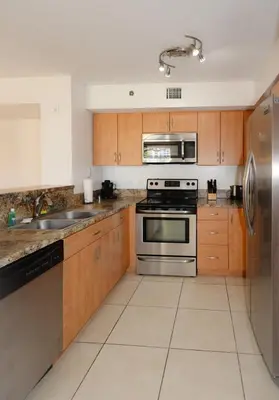 a kitchen with wooden cabinets and stainless steel appliances at 2 Luxury Bedrooms at Yacht Club de Aventura in Miami