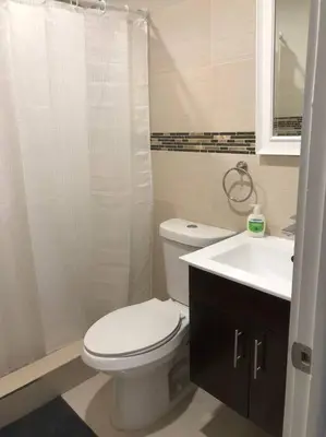 a white bathroom with a toilet and a sink at CHIC AND MODERN APARTMENT STEPS FROM THE BEACH in Miami Beach