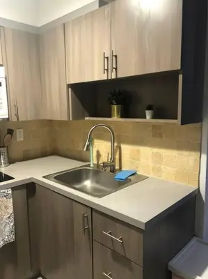 a kitchen with a sink and wooden cabinets at CHIC AND MODERN APARTMENT STEPS FROM THE BEACH in Miami Beach