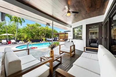 an outdoor patio with white furniture and a swimming pool at Casa Olan - Luxury Family Oasis 3BR North Miami Beach Villa with Saltwater Pool & Canal Views in Miami