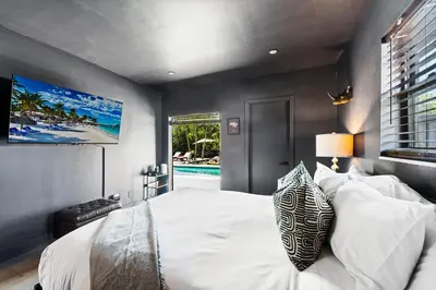 a bedroom with a bed and a tv on the wall at Casa Olan - Luxury Family Oasis 3BR North Miami Beach Villa with Saltwater Pool & Canal Views in Miami