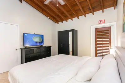 a bedroom with a white bed and a tv at Walk to Beach Luxury 5BR & 3BA Villa Hollywood Lakes in Hollywood