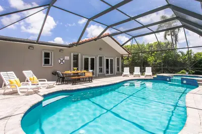 a swimming pool with chairs and a table and a house at Fabulous 5BR & 3BA Villa near Hollywood Beach in Hollywood