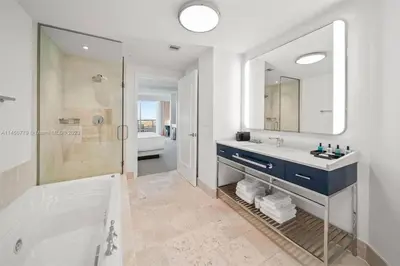 a bathroom with a tub and a sink and a mirror at Fontainebleau Miami Beach Junior Suite in Miami Beach