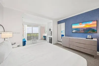 a bedroom with a large bed and a blue wall at Fontainebleau Miami Beach Junior Suite in Miami Beach