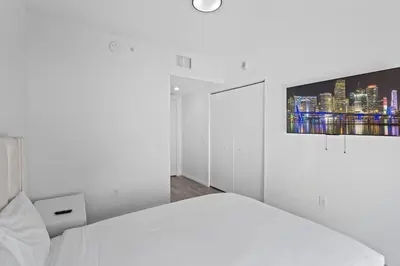 a white bedroom with a bed and a tv on the wall at Majestic unit in the heart of Downtown Miami in Miami